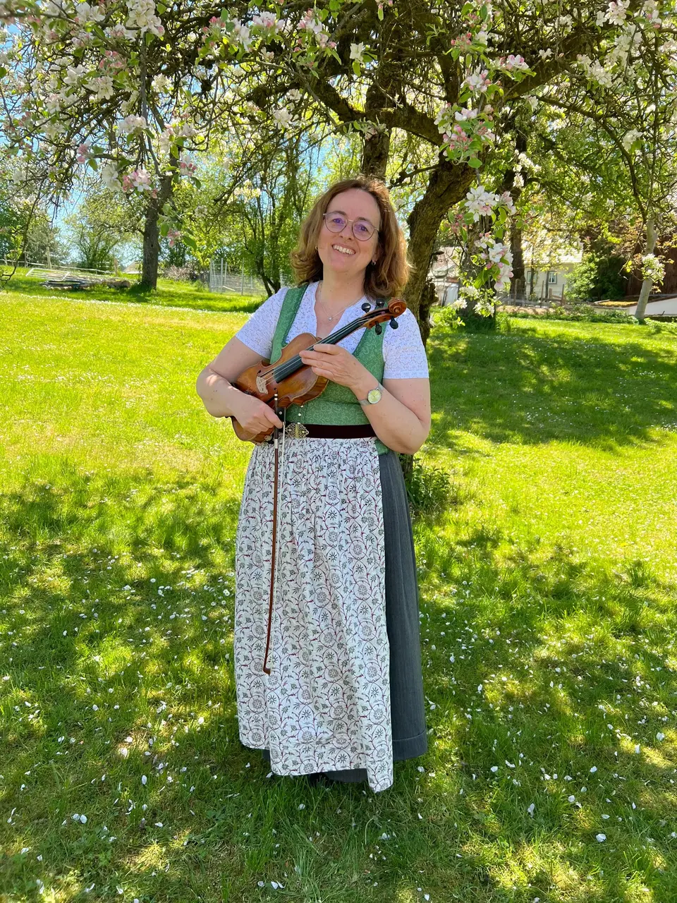 Gabriele Haindl mit ihrer Geige im blühenden Obstgarten