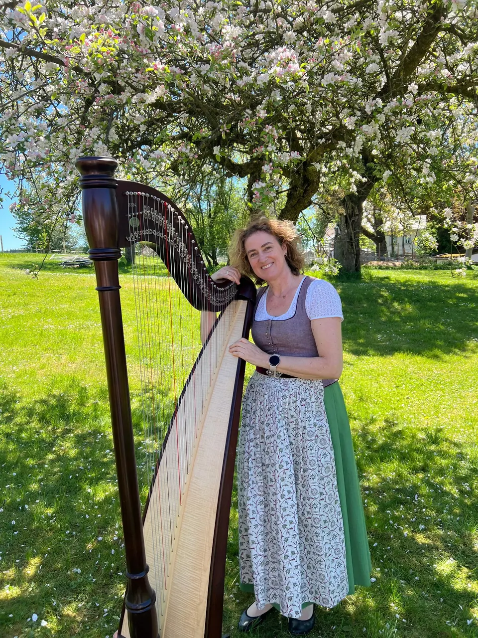 Veronika Dupuy mit ihrer Harfe im blühenden Obstgarten